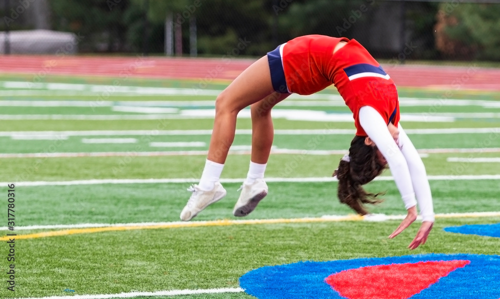 Photography Cheerleader doing back flips on turf field