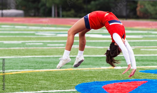 Cheerleader doing back flips on turf field
