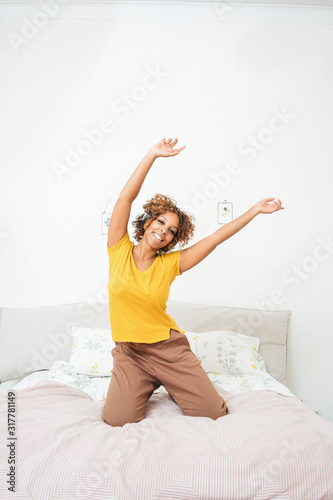 Happy young woman listening to music with headphones on the bed at home photo