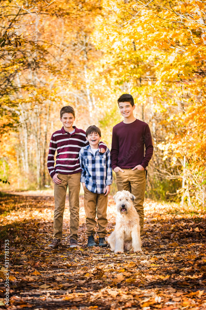 Portrait of three boys and their dog on leafy trail on autumn day. Portrait of three boys and their dog on leafy trail on autumn day.