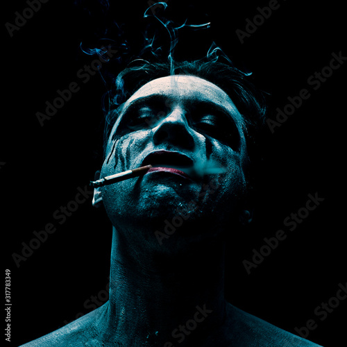 Man covered by paint smoking a cigarette photo