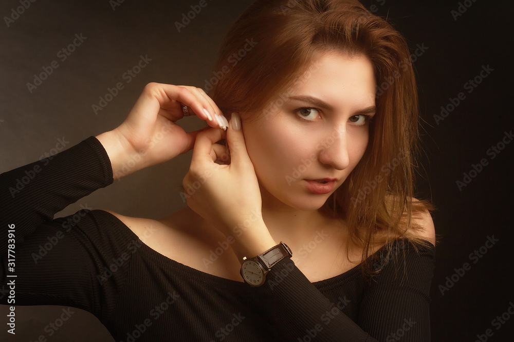 Portrait in the photo Studio of a brown-haired girl, on a black background in black clothes with open shoulders. Short hair. Portrait in the photo Studio of a brown-haired girl, on a black background in black clothes with open shoulders. Short hair.
