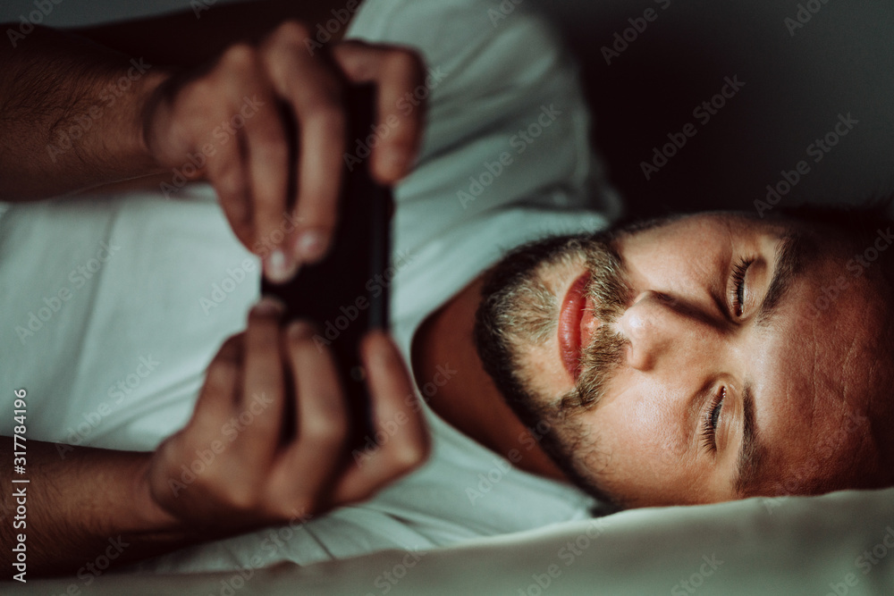 Young man cannot sleep and is watching something on his phone Young man cannot sleep and is watching something on his phone