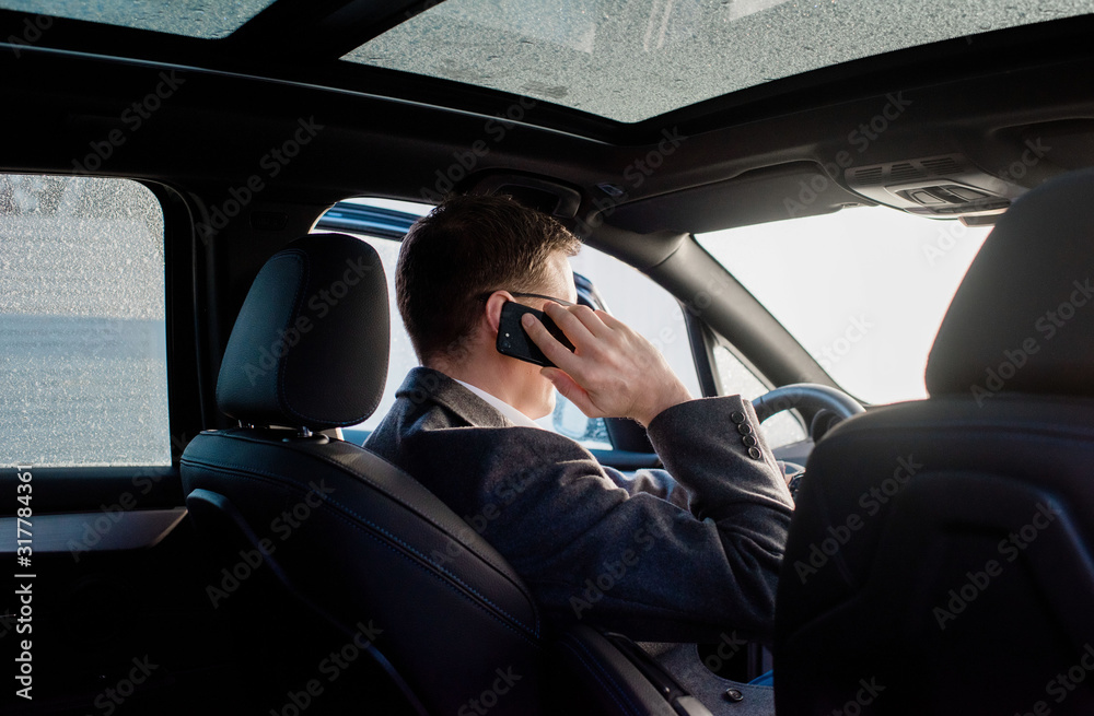 businessman talking on the phone in his frosty car at home businessman talking on the phone in his frosty car at home