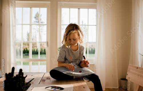 young girl drawing on her hand and face at home photo