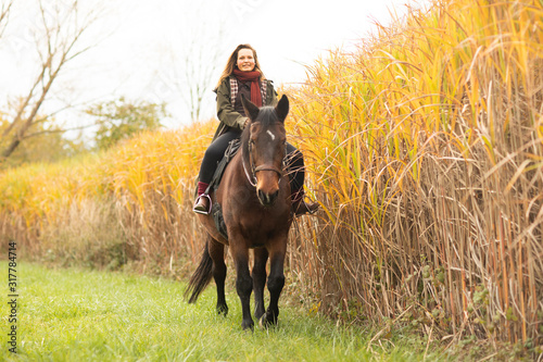 young horsewoman with a horse outeside riding photo