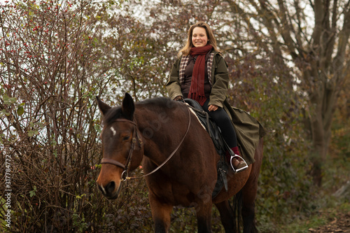 young horsewoman with a horse outeside riding photo