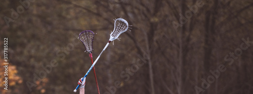 raised lacrosse sticks against the backdrop of autumn trees