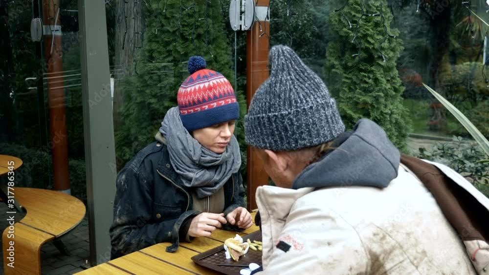 homeless couple, man and woman eating leftovers from a table in a street cafe homeless couple, man and woman eating leftovers from a table in a street cafe