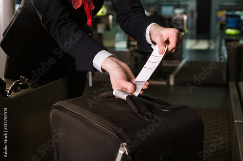 airport employee fastens luggage tag on a suitcase