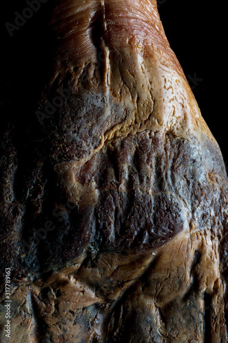 The art of Spanish Iberian ham. Whole leg with artistic look on a black background. © PhotoStk