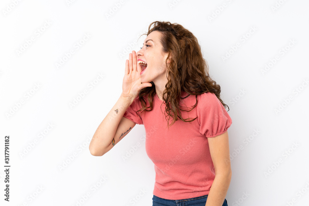 Young pretty woman over isolated background shouting with mouth wide open to the lateral Young pretty woman over isolated background shouting with mouth wide open to the lateral