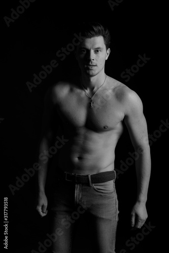 barechested guy with a dramatic light in the Studio on a black background. black and white