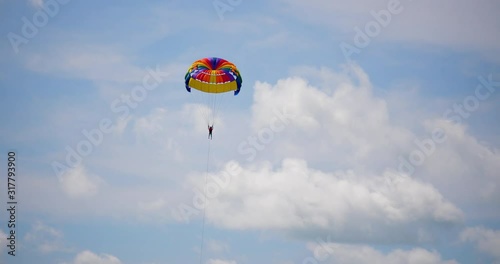 parasailor flying in the sky with parachute  parasaling parachute moving in the sky tourist parasaling in sunny day photo