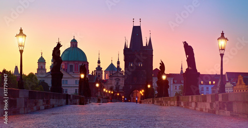 Charles Bridge in the morning, silhouette of Bridge Tower and saint sculptures with street lights in Prague, Czech Republic