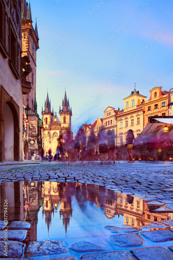 St Mary Tyn Church in Prague with reflection in a pool of water after Summer rain with tourists walking by towards Old Town Square. Prague, Czech Republic.