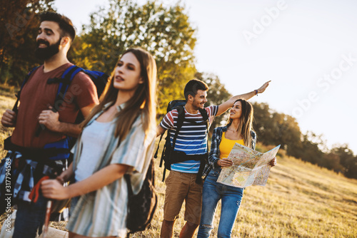 adventure, travel, tourism, hike and people concept - group of smiling friends walking with backpacks in nature