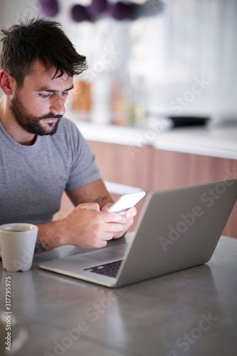 Sleepy man using his phone during breakfast.