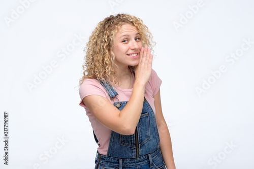 Beautiful young teenager woman teeling a secret to her friend. Gossip girl concept. Studio shot