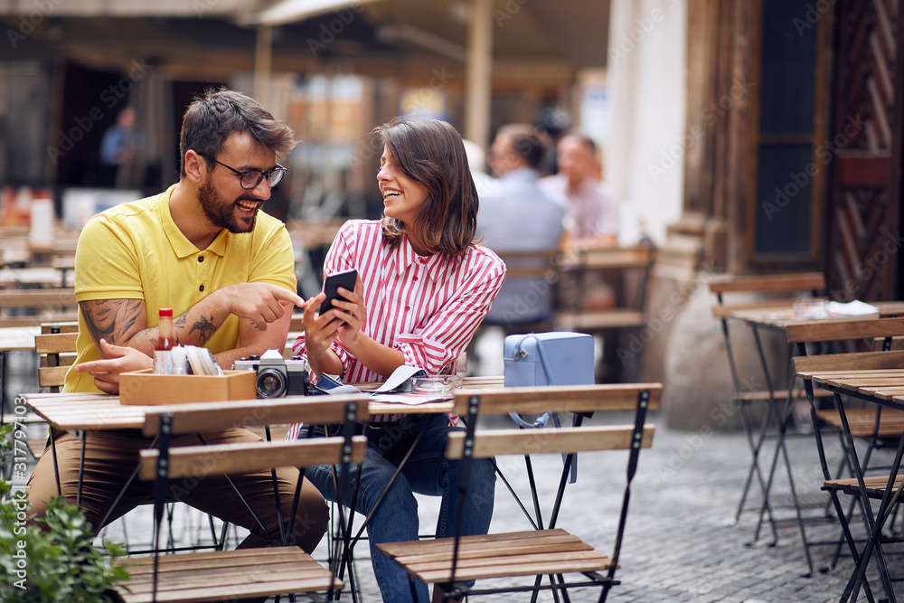 Couple of tourists consulting guide online at caffe Couple of tourists consulting guide online at caffe