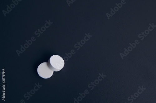 Two white pills on a dark background