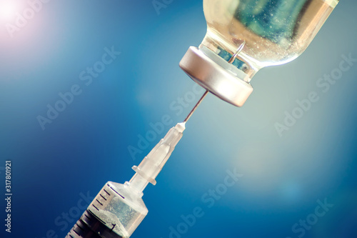 Foto A bottle with vaccine and syringe in front of blue background