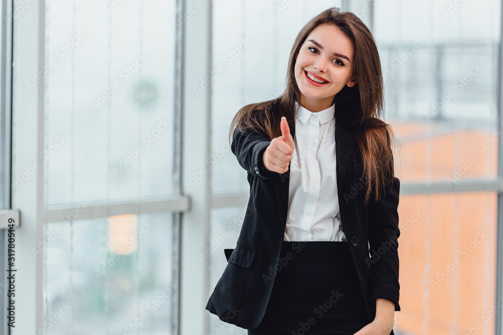 Pretty office employee showing thumb up isolated near window. Pretty office employee showing thumb up isolated near window.