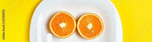 Top view of the two orange slices at the white dish lies on the bright yellow background. Healthy food  detox  diet concept