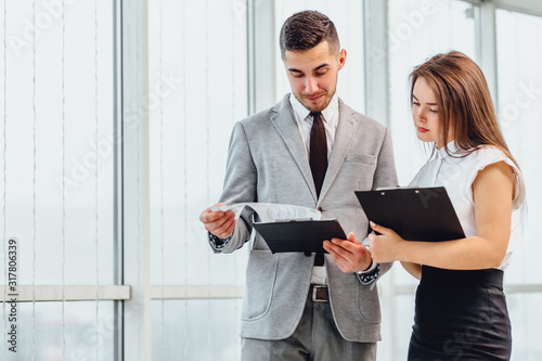 Successful man and woman making business plan, comparing each other researches.