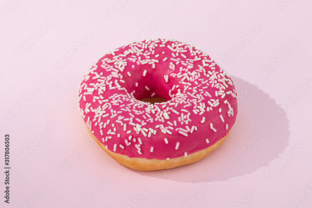 Pink donut with icing on pastel pink background Pink donut with icing on pastel pink background