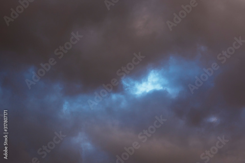 Dark clouds covering the blue sky. Abstract background. © Yevhenii
