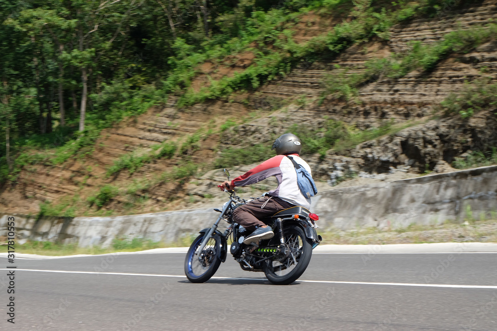 Man riding a classic motorcycle on highway of mountain Man riding a classic motorcycle on highway of mountain