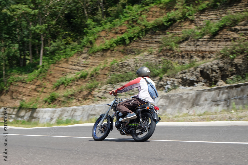 Man riding a classic motorcycle on highway of mountain