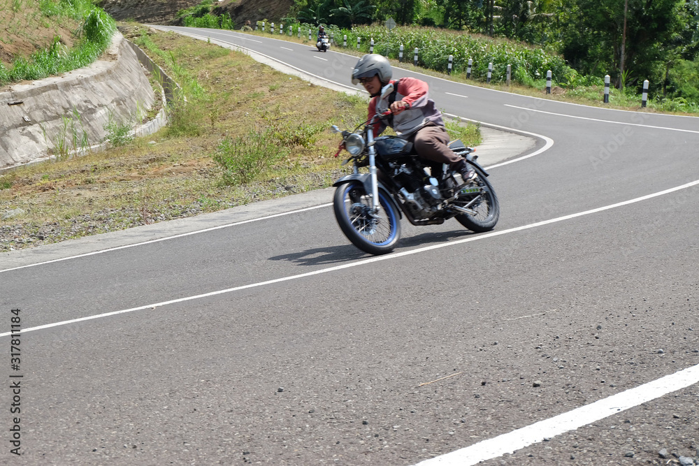 Man riding a classic motorcycle on highway of mountain