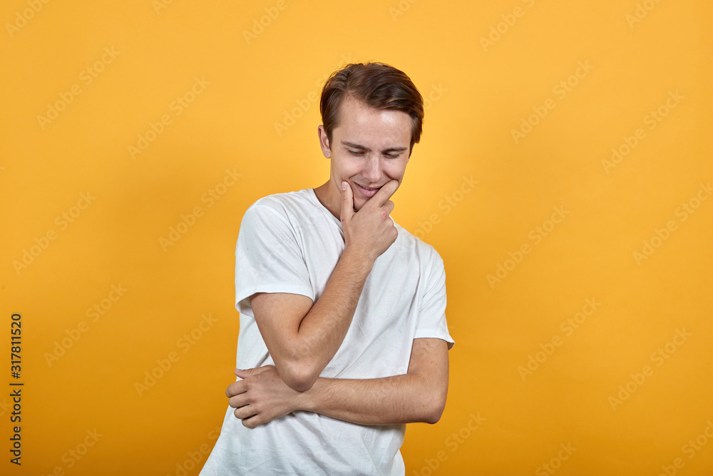 Young conceived man tilted his head down thinks or dreams and supports chin with hand