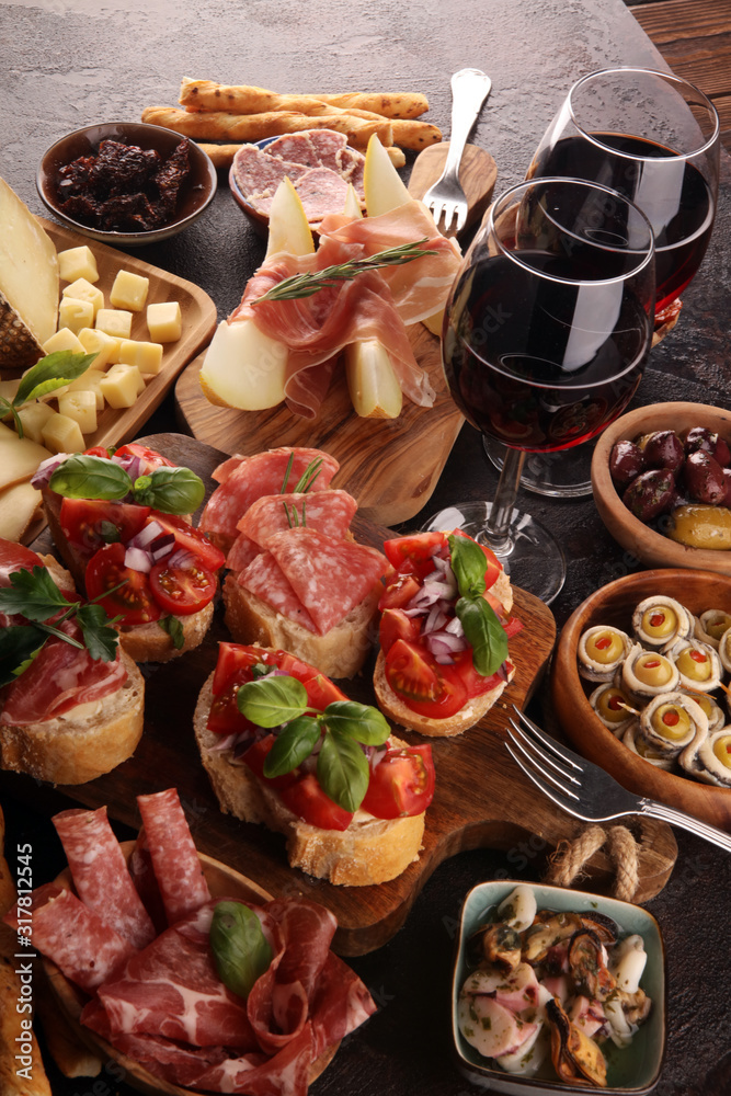 Italian antipasti wine snacks set. Cheese variety, Mediterranean olives, seafood salad, Prosciutto di Parma, tomatoes, anchovy and wine in glasses Italian antipasti wine snacks set. Cheese variety, Mediterranean olives, seafood salad, Prosciutto di Parma, tomatoes, anchovy and wine in glasses