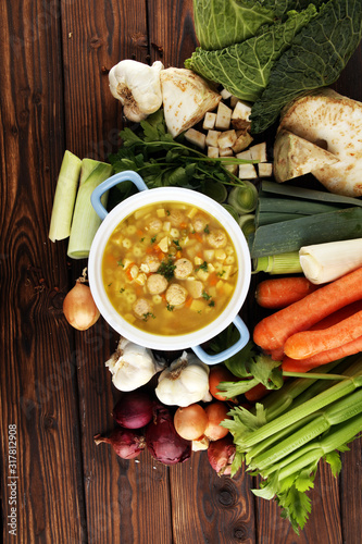 Broth with marrow dumplings and carrots, onions various fresh vegetables in a pot - colorful fresh clear spring soup. Rural kitchen scenery bouillon