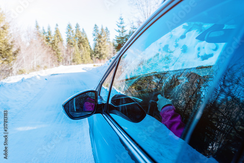 View of the rearview mirror of a moving car on a snowy, winter surface. Concept of safe driving in winter conditions