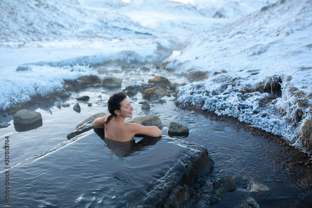 The girl bathes in a hot spring in the open air with a gorgeous view of the snowy mountains. Incredible iceland in winter The girl bathes in a hot spring in the open air with a gorgeous view of the snowy mountains. Incredible iceland in winter