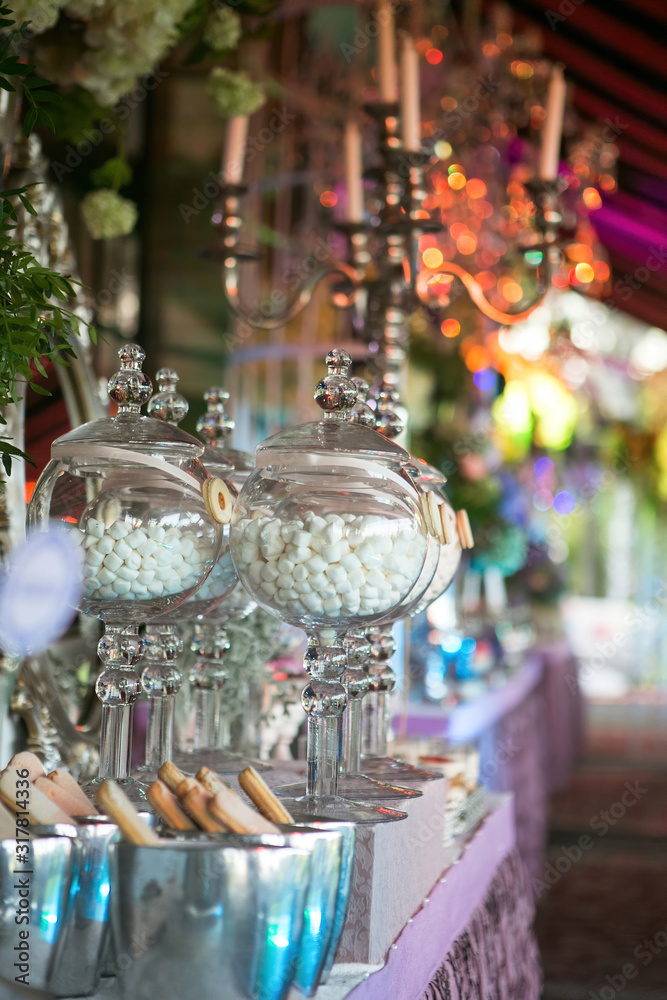 A sweet table with desserts and sweets in purple colors. Marshmallows in glass vases. Decor luxury wedding celebration.