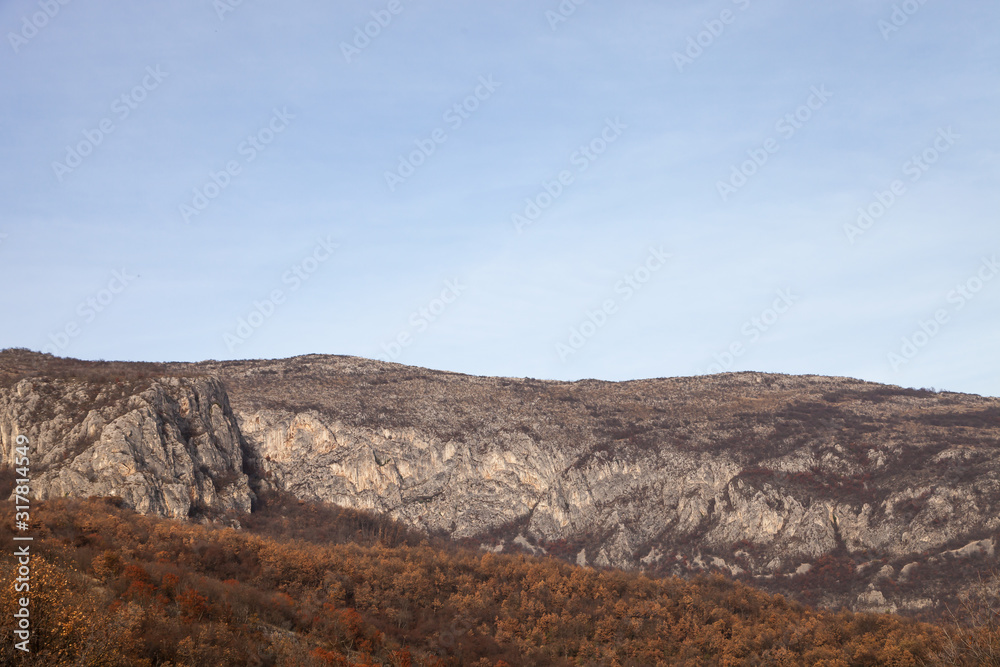 Rocky peaks and vivid autumn colors of the forest on Svrljig (Svrljiske) mountains in Serbia under a clear blue sky