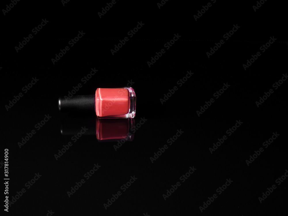 Pink nail polish bottle lying on black background with refection Pink nail polish bottle lying on black background with refection