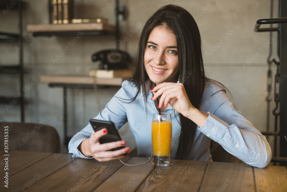 Positive young woman in casual clothes drinking fresh beverage using phone sitting at table in cafe Positive young woman in casual clothes drinking fresh beverage using phone sitting at table in cafe