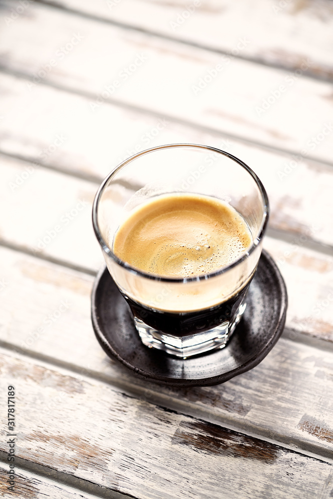 Coffee in glass cup on bright wooden background. Coffee in glass cup on bright wooden background.