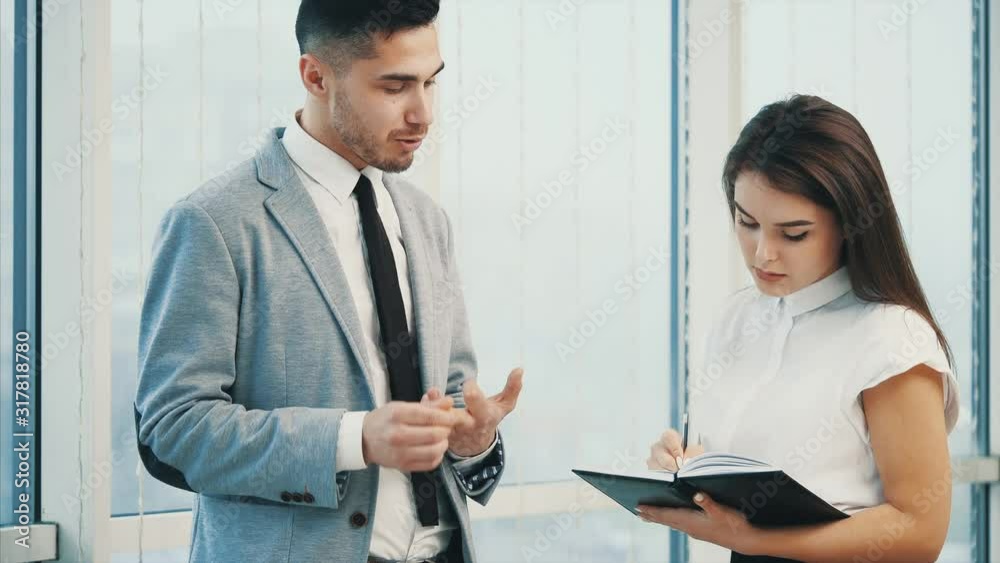 Confident business man is giving directions to his coworker. Blurred white panoramic background. Close up. 4K.