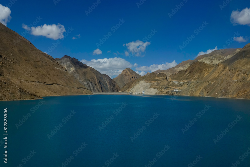 AERIAL: Breathtaking view of a large deep blue lake by the Manak Dam in Tibet.