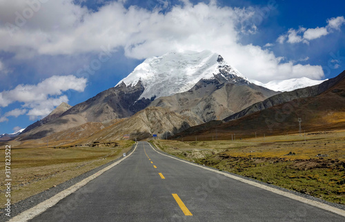 Straight road leads towards the foothills of a majestic Himalayan glacier.