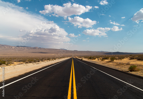 Expansive desert road with puffy clouds