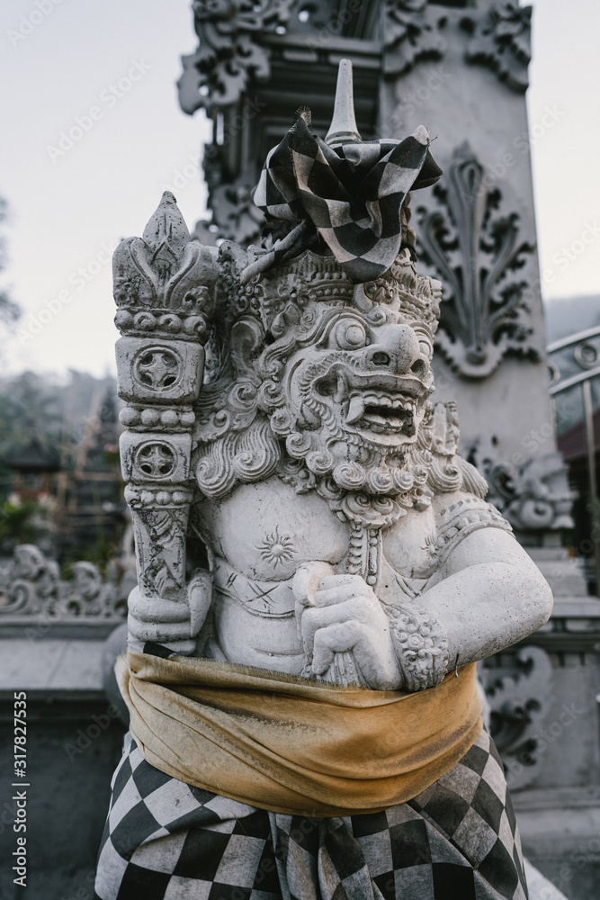 Traditional demon guards statue carved in stone at the temple in Bali island