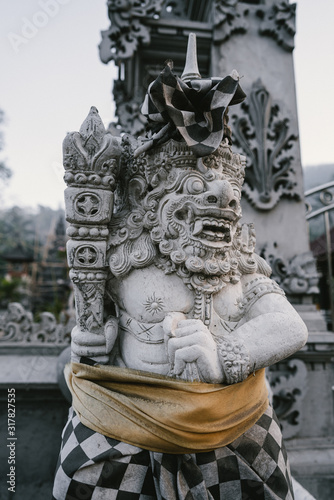 Traditional demon guards statue carved in stone at the temple in Bali island © irengorbacheva